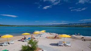 a beach with chairs and umbrellas and people on it at Apartments in Klimno/Insel Krk 12514 in Klimno