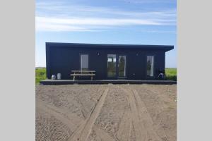 Hólmasel Riverside Cabin 1 في Arabaer: منزل صغير أسود يجلس على قمة ميدان ترابي