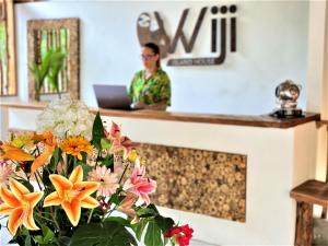 a woman sitting at a reception desk with flowers at Isla Fuerte - Wiji Island House in Puerto Limón