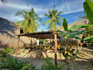 a straw hut with palm trees in the background at Isla Fuerte - Wiji Island House in Isla Fuerte