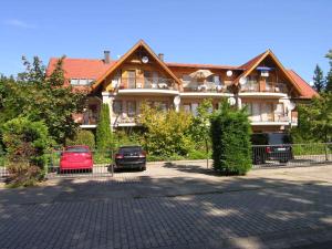 ein großes Haus mit zwei Autos davor geparkt in der Unterkunft Apartment in Balatonlelle 34439 in Balatonlelle
