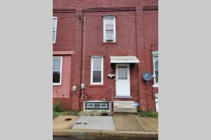 a red brick house with a white door and stairs at Nice and cozy home for a business or family stay. in Johnstown
