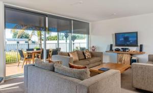 a living room with a couch and a table with a television at Ohope Beach Resort in Ohope Beach