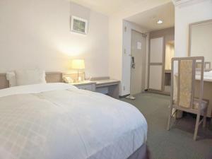 Schlafzimmer mit einem Bett, einem Schreibtisch und einem Stuhl in der Unterkunft Hotel New Century in Okinawa