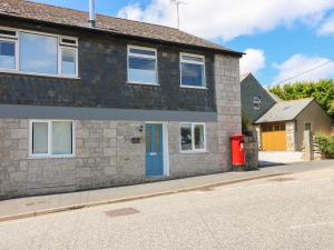 a brick house with a blue door and a red mailbox at The Old Post Office in Helston