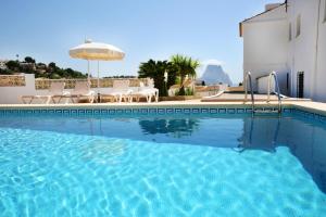 a pool with chairs and an umbrella next to a building at Villa Canuta De Ifach - Costa CarpeDiem in Calpe