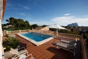 uma piscina num pátio com cadeiras e um guarda-sol em Villa Robin - Costa CarpeDiem em Calpe