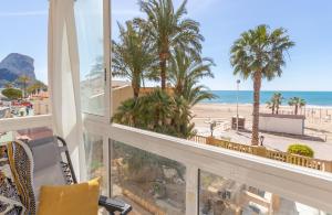 een kamer met uitzicht op het strand en de palmbomen bij Apartamento Joya I - Costa CarpeDiem in Calpe