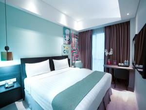 a hotel room with a large bed and a desk at favehotel Puri Indah Jakarta in Jakarta