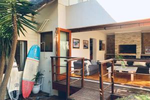 Casa con terraza con tabla de surf y sofá en J Bay Surf Villa, en Jeffreys Bay