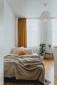 a white bedroom with a large bed with a blanket at Residential Barona Apartments in Riga Centre in Rīga