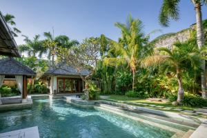 einen Pool im Hinterhof eines Hauses mit Palmen in der Unterkunft The Maya Seminyak Villas in Seminyak