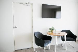 um quarto com uma mesa e duas cadeiras e uma televisão em Noosa Heads Motel em Noosa Heads