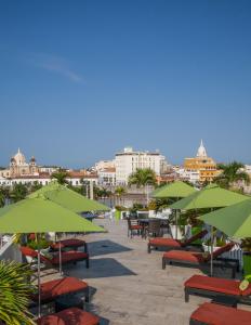 un patio avec des parasols verts, des tables et des chaises dans l'établissement Hotel Monterrey, à Carthagène des Indes