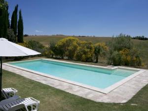 een zwembad met 2 stoelen en een parasol bij Belvilla by OYO Farmhouse in Tuscany with Garden in Castelnuovo Berardenga