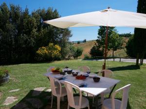 een tafel met een witte paraplu en wat fruit erop bij Belvilla by OYO Farmhouse in Tuscany with Garden in Castelnuovo Berardenga