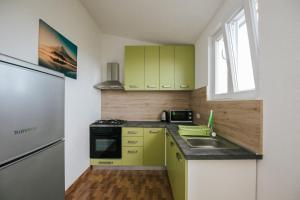 una pequeña cocina con armarios verdes y fregadero en tomislav, en Trogir