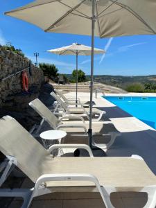 a row of chairs and umbrellas next to a pool at Quinta BEMBOA Turismo Espaço Rural in Aricera