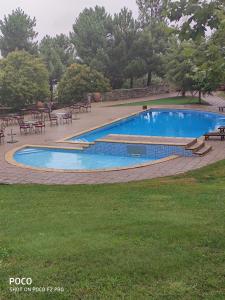 a swimming pool with tables and chairs in a park at Montanhas do Douro in Paredes da Beira