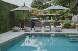 a pool with lounge chairs and umbrellas next to at La Maison Des Papillons in Deerlijk