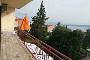 - un balcon avec un parasol orange et quelques arbres dans l'établissement Spacious 2-room apartment with beautiful sea view, à Crikvenica