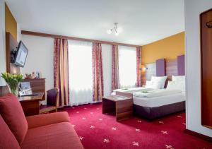 a hotel room with a bed and a couch at TIPTOP Hotel Burgschmiet Garni in Nürnberg