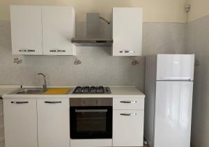 eine weiße Küche mit einem Herd und einem Kühlschrank in der Unterkunft Villa Green - Irpinia in Venticano