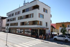 dos personas de pie en frente de un edificio en una calle en Rezidence Šumava, en Železná Ruda