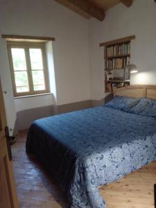 a bedroom with a bed with a blue bedspread and two windows at Ca' del Rì in Gargnano