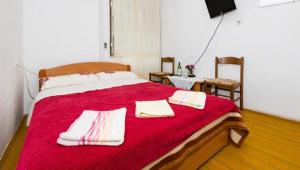 a bedroom with a large red bed with towels on it at Rooms Kisic in Dubrovnik