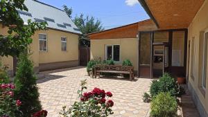 a patio with a bench and flowers in a courtyard at Evergreen Guesthouse in Karakol
