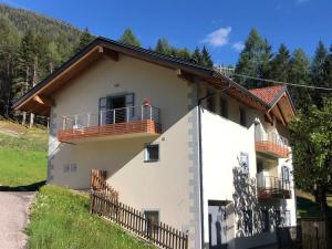 a white house with a balcony and trees at B&B Le Stagioni di Stava in Tesero