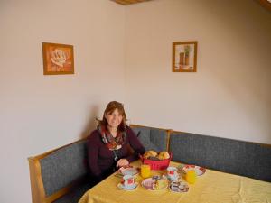 Pension Schneider, Ferienwohnung في باد غوغنغ: امرأة تجلس على طاولة مع وعاء من الطعام