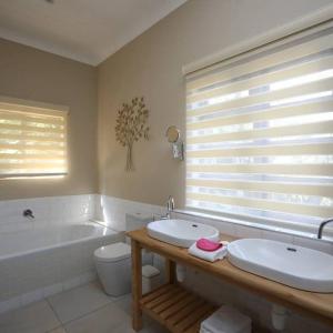 ein Badezimmer mit zwei Waschbecken, einer Badewanne und einem WC in der Unterkunft Ben's Bed and Breakfast in Pretoria