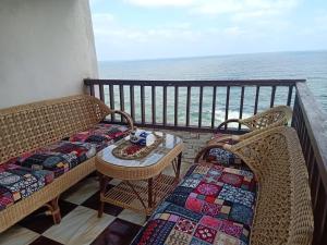 sporting sea view two bedroom appartement في الإسكندرية: بلكونه فيها كرسيين وطاولة والمحيط