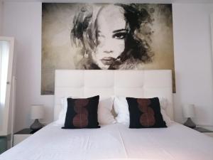 a bedroom with a white bed with a painting above it at Alexandra House in Costinesti