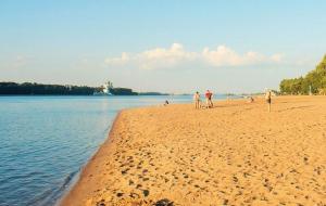 a group of people standing on a beach next to the water at MAXROOMS Volga HOLLYWOOD in Rybinsk