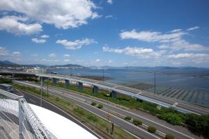 a bridge over a highway next to a body of water at Global Resort Miyajima View in Hatsukaichi