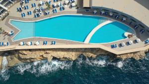 an overhead view of a pool on a cliff next to the ocean at Paradise Bay Resort in Mellieħa