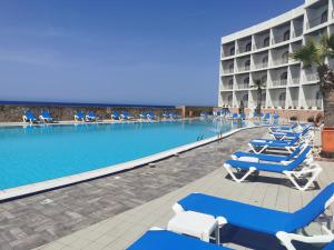a swimming pool with blue and white chairs and a hotel at Paradise Bay Resort in Mellieħa