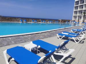 a group of blue and white lounge chairs next to a swimming pool at Paradise Bay Resort in Mellieħa