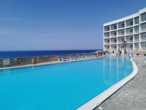 a large swimming pool next to a hotel and the ocean at Paradise Bay Resort in Mellieħa