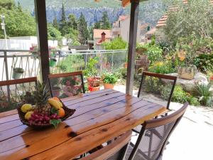 a wooden table with a bowl of fruit on a porch at Apartment Bajama in Omiš