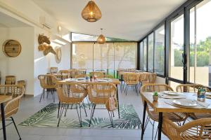 a restaurant with tables and chairs and windows at Hôtel L'Escale Coté Port in LʼÎle-Rousse