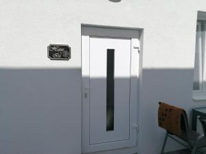 a white door with a sign on it next to a chair at Zum Hofgassl Haus Isi in Mörbisch am See