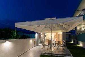 - un grand parasol blanc sur la terrasse la nuit dans l'établissement AURA APARTMENTS, à Keramoti