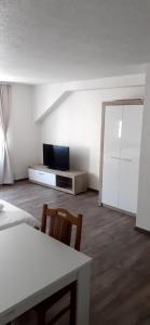 uma sala de estar com uma televisão e uma mesa e cadeiras em Guest house Erdan em Plav