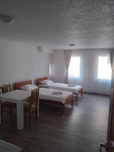 a room with three beds and a table and chairs at Guest house Erdan in Plav