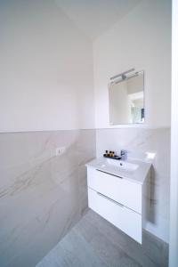 Baño blanco con lavabo y espejo en Beat House&Apartments, en Agrate Brianza