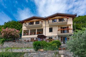 dom na wzgórzu z kwiatami na balkonach w obiekcie Foresteria Lago di Como w mieście Menaggio